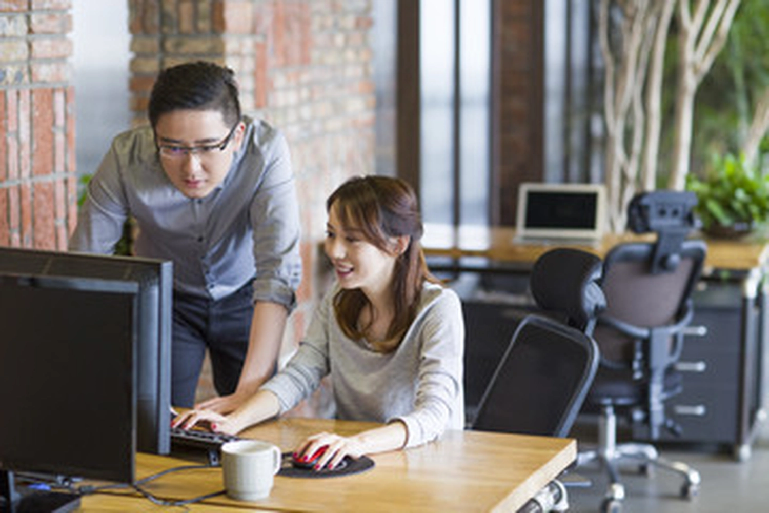 Jobway Germany - Internationale Rekrutierung von Fachkräften - Ein Mann und eine Frau arbeiten in einem Büro gemeinsam an einem Computer.